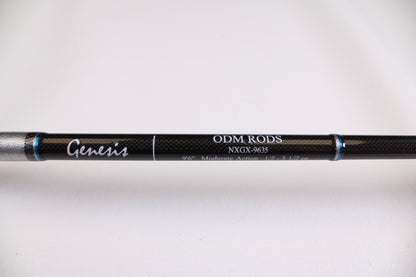 A close-up of an ODM Rods Genesis Surf NGX-9635 9'6" 2 Piece Used Spinning Rod in excellent condition, showing its black finish with silver and blue accents. Eligible for rod and reel trade-in—earn store credit on your next purchase.
