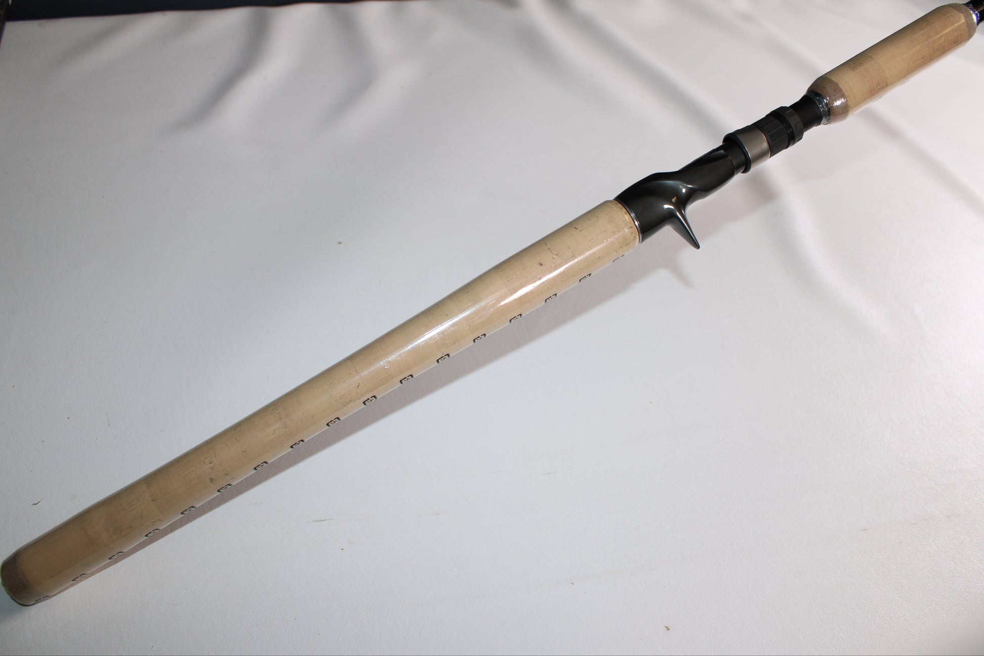A Shimano SKIXX SKC80XH Used Casting Rod in mint condition, with a light wood handle and black reel seat, is displayed diagonally on a plain white surface—perfect for our rod and reel trade-in program.