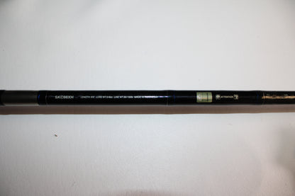 A close-up of the Shimano SKIXX SKC86XH Used Casting Rod in mint condition, with the model number and specs printed in white, plus two small green and gold labels, lying on a white surface.