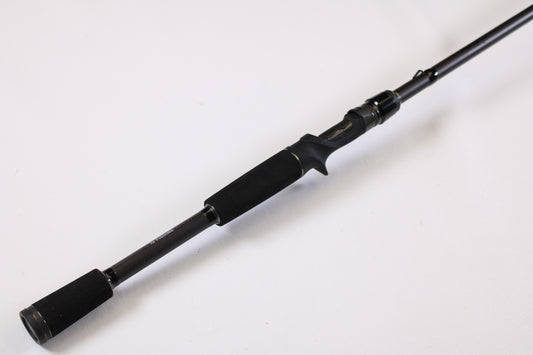 The 13 Fishing Muse Black MB2C74H 7'4" Heavy Used Casting Rod in excellent condition by 13 Fishing features a sleek black design with a foam handle, ideal for the rod and reel trade-in program, shown on a plain white background.