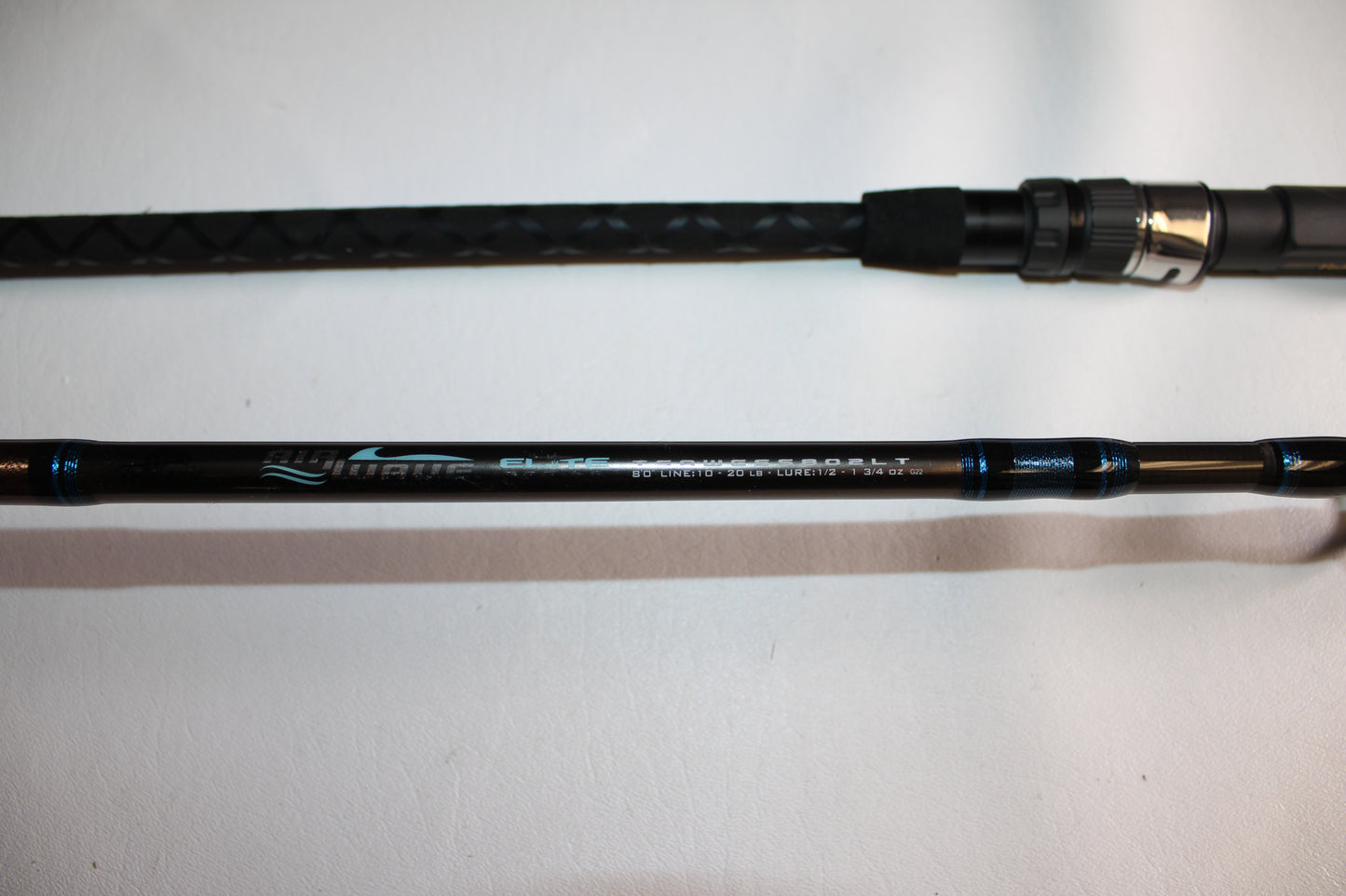 A close-up of the Tsunami Air Wave Elite TSAWESS802LT 8'0" 2-piece used spinning rod in excellent condition, showcasing its handle and model details—ideal for those interested in quality pre-owned Tsunami rods.