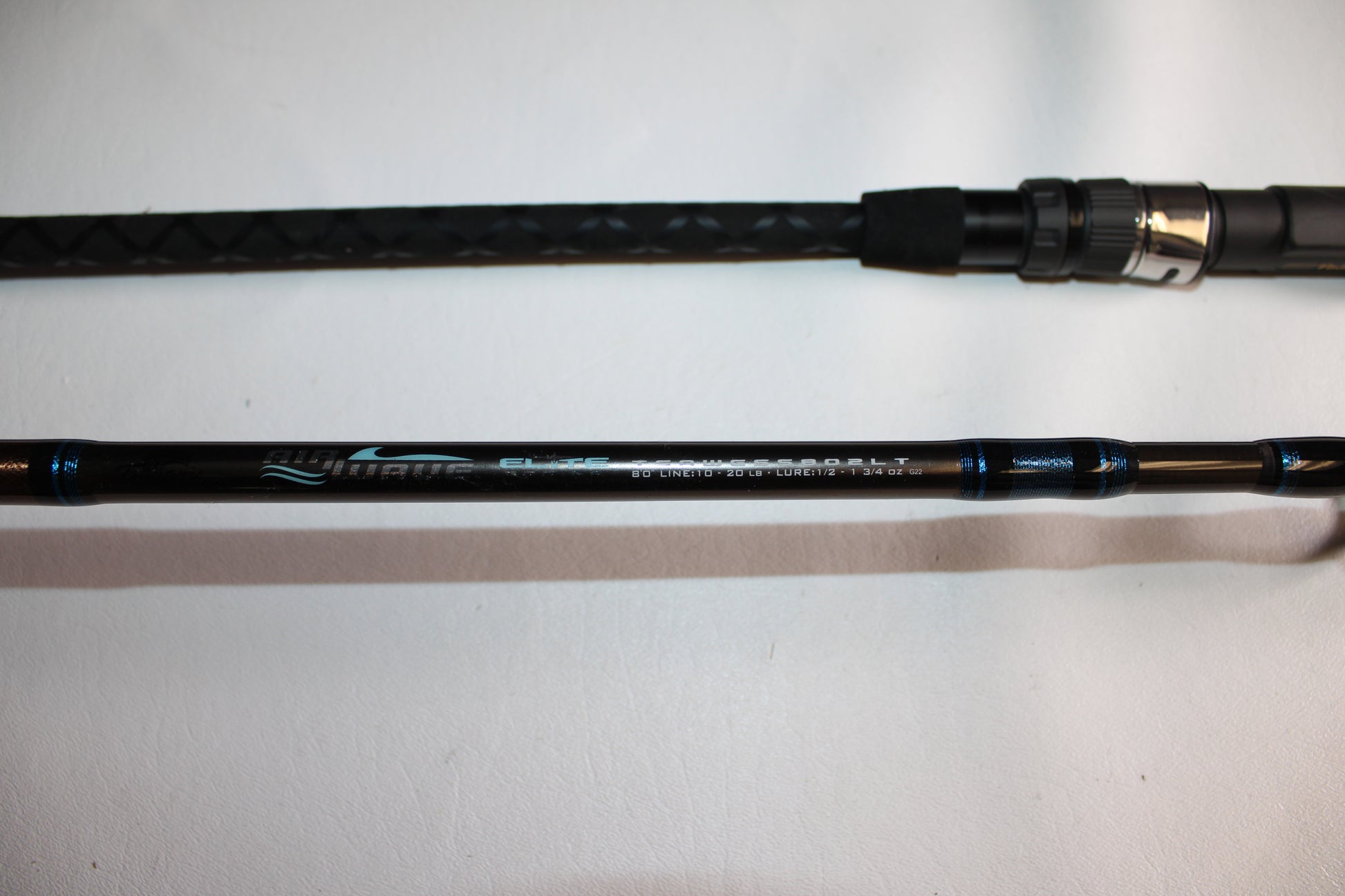 A close-up of the Tsunami Air Wave Elite TSAWESS802LT 8'0" 2-piece used spinning rod in excellent condition, showcasing its handle and model details—ideal for those interested in quality pre-owned Tsunami rods.