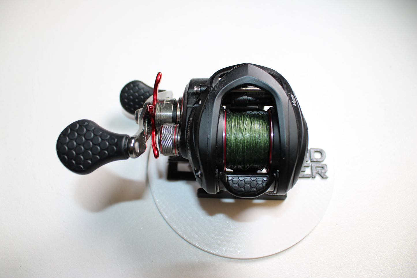 A Lew's Tournament MP TS1SHMPL 7.5:1 baitcasting reel in excellent used condition with green line, shown on a white surface with a silver base. Trade in your old gear for store credit through our Rod and Reel Trade-In Program!.