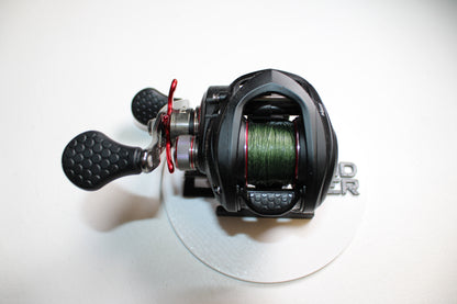 A Lew's Tournament MP TS1SHMPL 7.5:1 baitcasting reel in excellent used condition with green line, shown on a white surface with a silver base. Trade in your old gear for store credit through our Rod and Reel Trade-In Program!.