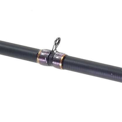 The ALX ENOX Casting Rod BMJ 7'2" Medium Heavy+ | E28645FC features a black textured surface made from 1100T Toray carbon fiber. It includes a metallic eyelet, two metal rings, and a center loop for line attachment, all displayed against a plain white background.
