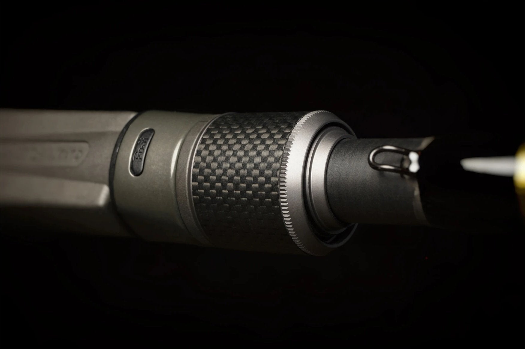 Close-up of the Falcon Cara Casting Rod Deep Runner 7'3" Medium Heavy (CC-5-173DR) tip, showcasing a metallic, textured grip and sharp hooked element—carbon fiber crafted—set against a dark background.