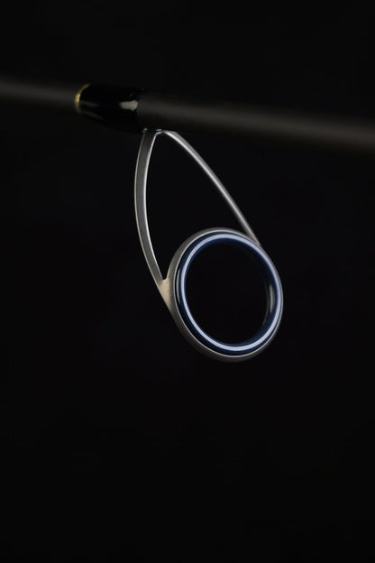 Close-up of the Falcon Cara Spinning Rod Medium Spin 7'0" (CS-4-17) guide against a dark background, showcasing its metallic ring and premium Fuji component support structure.