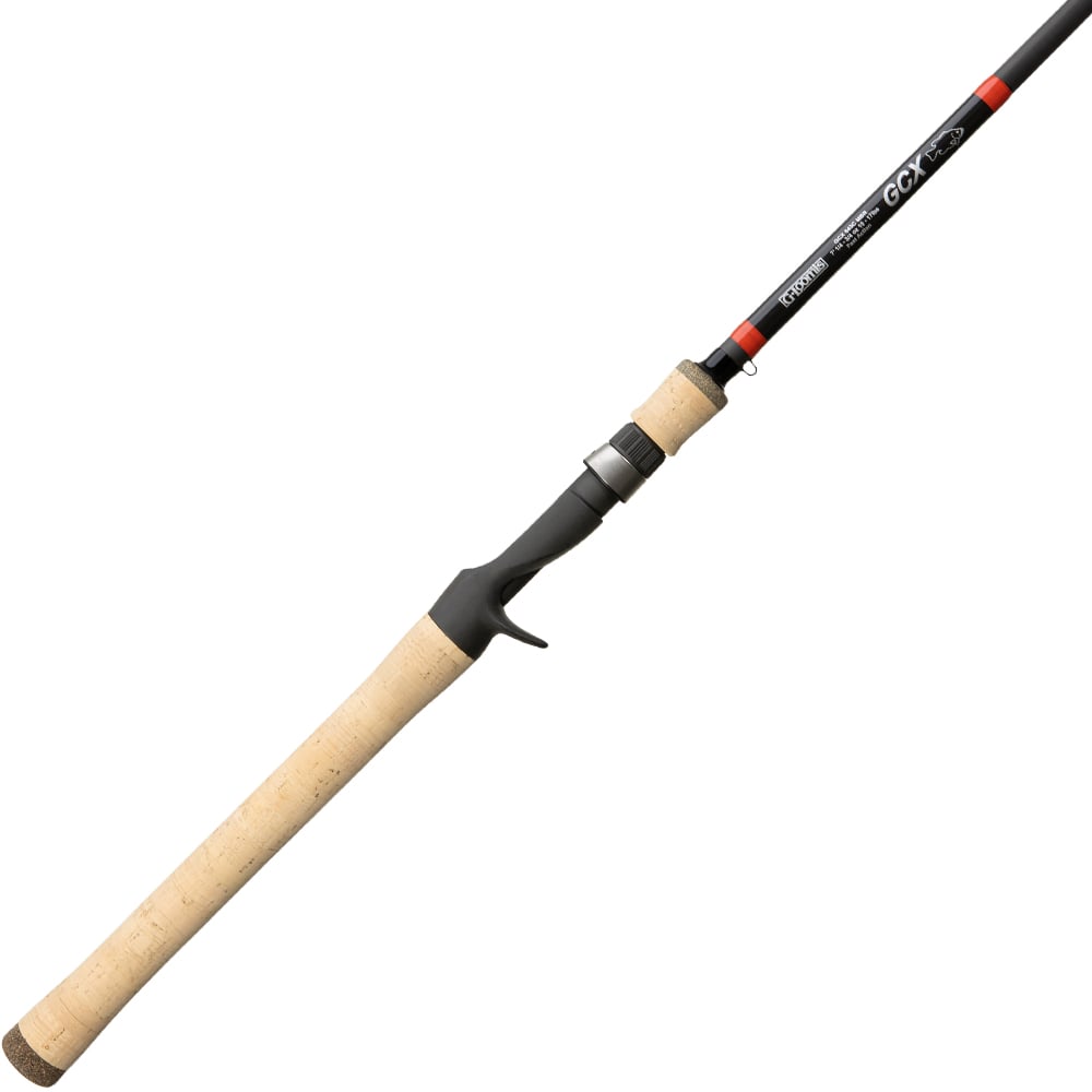 The G. Loomis GCX Mag Bass Casting Rod 843C MBR 7'0" Medium Heavy features a long cork handle, black reel seat, slender black blank with red and white accents near the tip, and a trigger grip for added control.