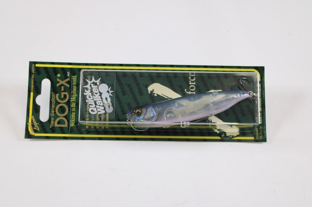 The Megabass Dog-X Quick Walker, a pencil bait fishing lure by Megabass, features a realistic silver-blue fish design with a one-knock sound, packaged on green and yellow striped cardboard.