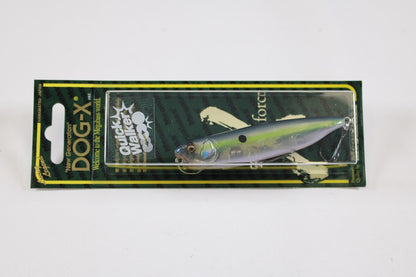 A packaged Megabass Dog-X Quick Walker pencil bait fishing lure, featuring a green-yellow design and "Quick Walker" label, is displayed against a white background. The unique one-knock sound lure is visible through a clear plastic cover.