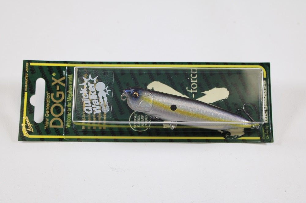 A packaged Megabass Dog-X Quick Walker by Megabass is shown. The silver lure with a dark top and black spot mimics a fish, and its one-knock sound attracts catches. Green packaging features yellow accents.