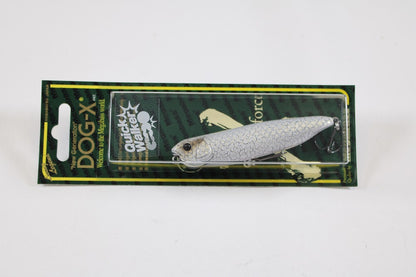 A packaged Megabass Dog-X Quick Walker pencil bait, featuring a silver fish-like design and known for its one-knock sound, is displayed on green and yellow Megabass cardboard backing.