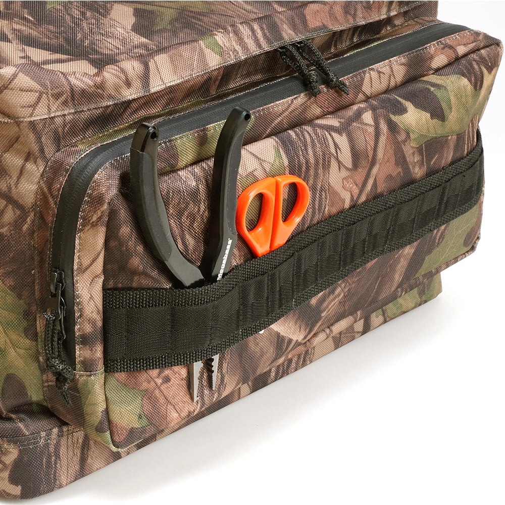 The Megabass Survival Bag II by Megabass, featuring a camouflage design and black strap, holds needle-nose pliers and orange-handled scissors. The bag is partially unzipped and displayed against a white background.
