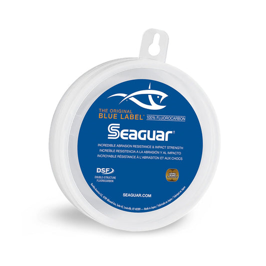 A spool of Seaguar Blue Label Fluorocarbon Leader by Seaguar, featuring superior knot strength and a blue and white label with a fish graphic and product details in English, Spanish, and French.