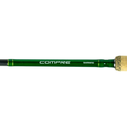 A close-up of the Shimano Compre Muskie Casting Rod 8'0" Heavy (CPCM80HJ) handle with cork grip, featuring "COMPRE" and "SHIMANO" logos in white—a quality heavy action rod for muskie casting.