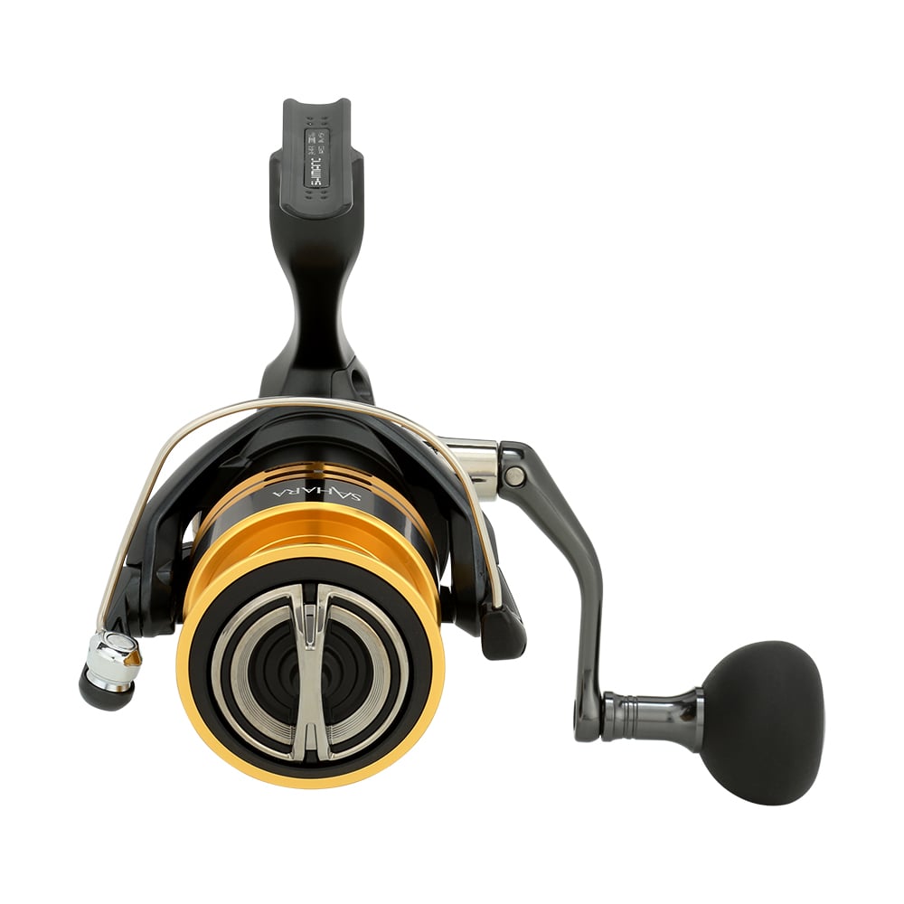 The Shimano Sahara FJ 5000XGFJ reel features a sleek black and gold design with an ergonomic handle, visible logo, and smooth metallic finish. Equipped with HAGANE Gear, this compact and stylish reel attaches seamlessly to a fishing rod for optimal use.