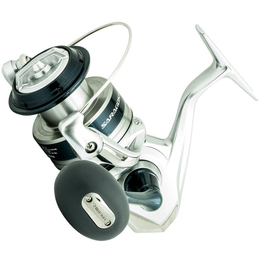 The Shimano Saragosa Spinning Reel 6000SWAHG 5.7:1 by Shimano features a silver and black design, large handle, "Saragosa" branding, visible spool, bail arm, and advanced Infinity Drive Technology for powerful saltwater fishing.