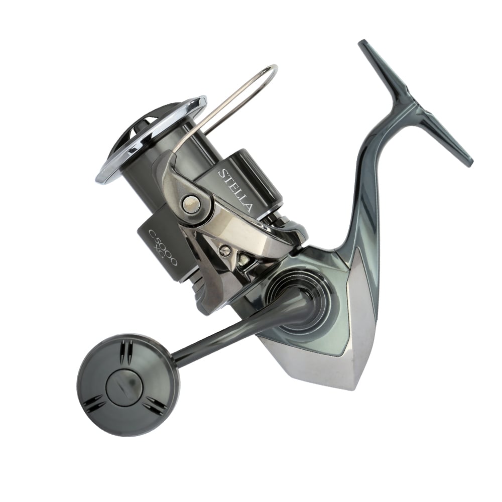 The Shimano Stella FK Spinning Reel 5000XGFK by Shimano is shown from the side, highlighting its silver and black design with the handle extended and both spool and bail arm visible.