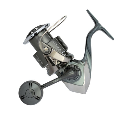 The Shimano Stella FK Spinning Reel 5000XGFK by Shimano is shown from the side, highlighting its silver and black design with the handle extended and both spool and bail arm visible.