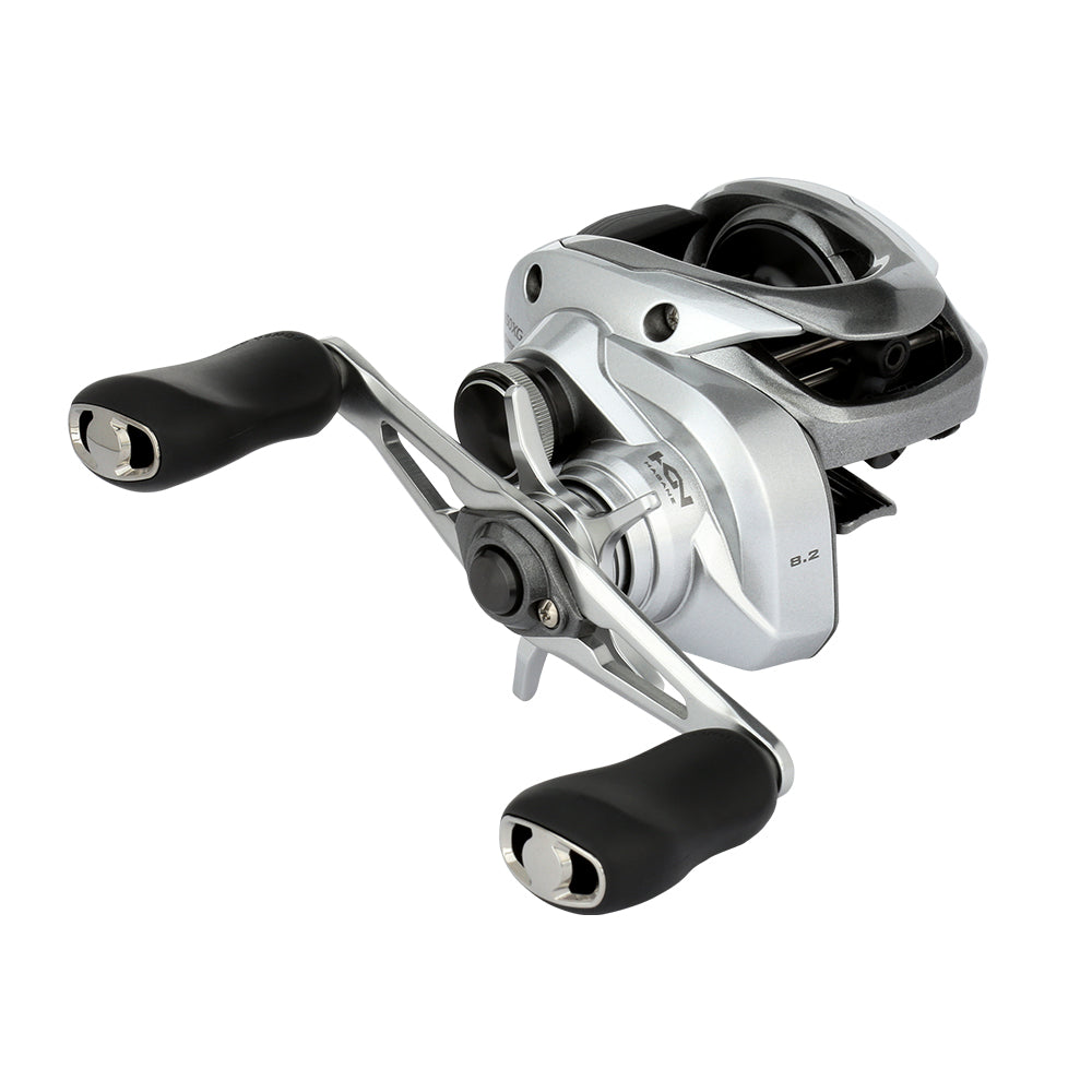 The Shimano Tranx 150A Casting Reel 8.2:1 Right Hand (TRX150XGA) by Shimano features a compact, modern silver design with black ergonomic handles, shown on a white background—perfect for saltwater fishing.