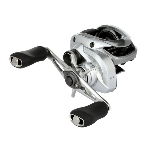 The Shimano Tranx 150A Casting Reel 8.2:1 Right Hand (TRX150XGA) by Shimano features a compact, modern silver design with black ergonomic handles, shown on a white background—perfect for saltwater fishing.