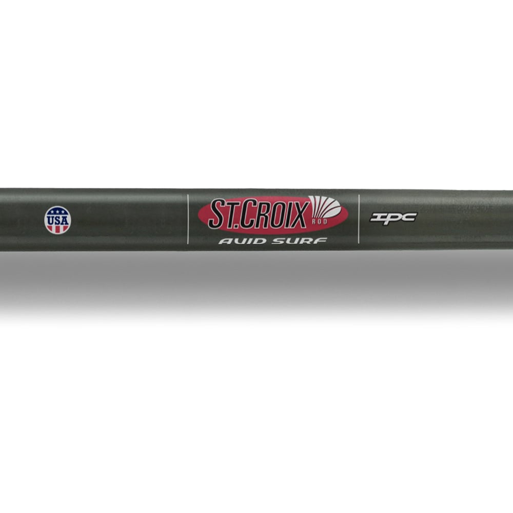 Close-up of a "St. Croix Avid Surf Spinning Rod 10'0" Medium" by americanlegacyfishing, featuring a USA emblem and "IPC" logo. Crafted from SCIII carbon for optimal casting, the sleek dark rod with red and white text combines style and high performance.