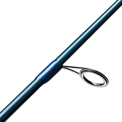 Close-up of a blue St. Croix Triumph Travel Spinning Rod 6'6" Medium Heavy TSR66MHF4 with a metal guide ring. It has a glossy finish, and the guide is secured with blue thread wraps. The plain white background emphasizes the elegance of this travel rod.
