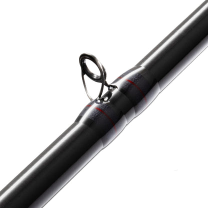 Close-up of a fishing rod guide on the St. Croix Victory Casting Rod 7'2" Medium Heavy Cranker from americanlegacyfishing. The metal loop guides the line seamlessly along the sleek, dark SCIII+ carbon fibers. Featuring a shiny finish and black and red thread wrapping, this Medium Heavy Cranker epitomizes precision against the plain white background.