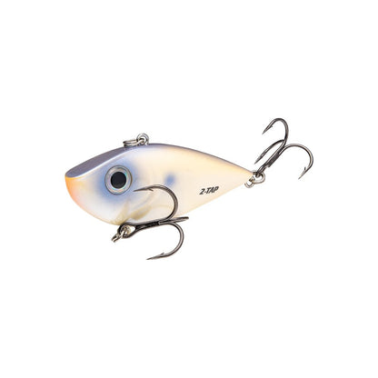 The "Strike King Red Eye Shad Tungsten 2 Tap" crankbait imitates a small fish with a metallic body, blue and white gradient, detailed eye, dual treble hooks, and lipless design—a precision lure by Strike King on a simple white backdrop.
