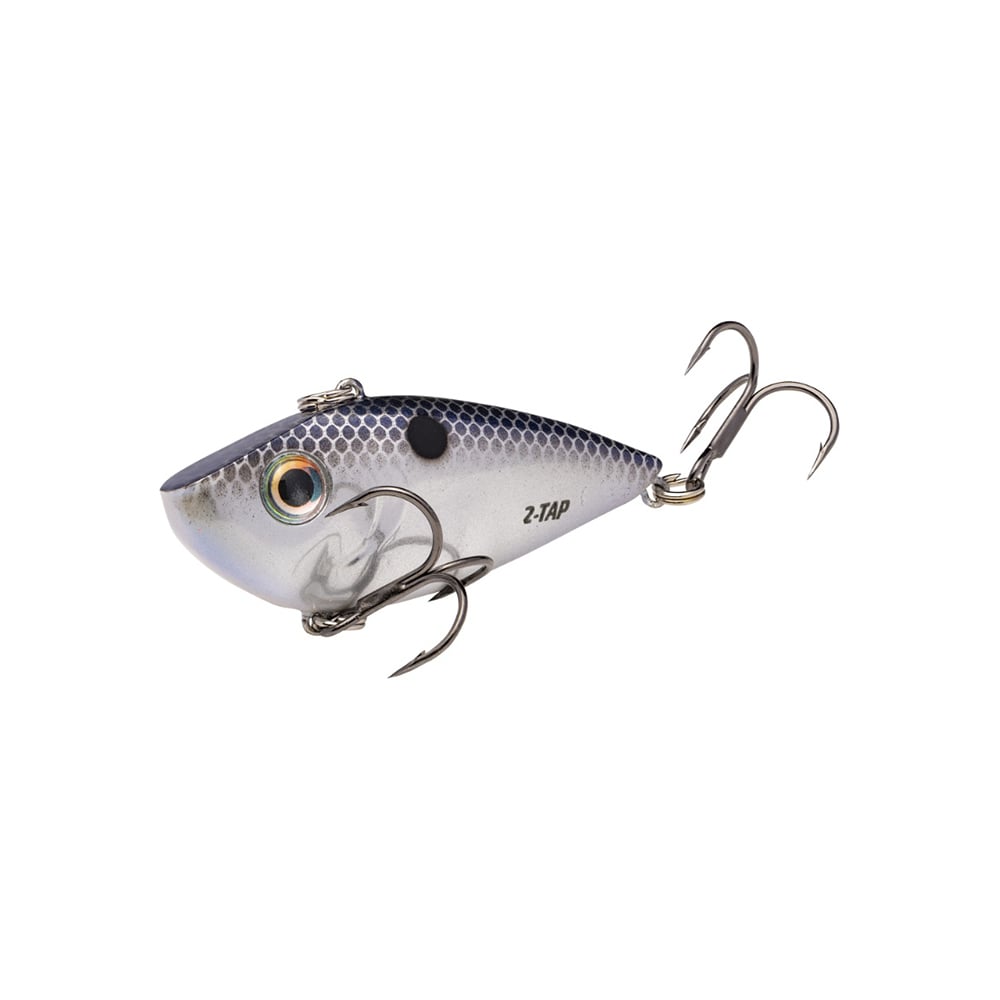 The Strike King Red Eye Shad Tungsten 2 Tap features a silver and blue fish shape with yellow and black eyes, two sharp treble hooks, and a textured body mimicking scales, making it the perfect lipless crankbait for anglers.