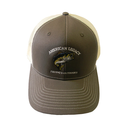 The American Legacy Fishing & Outdoors Bass Trucker Hat, in brown and white mesh, showcases an embroidered jumping fish and "American Legacy Fishing + Outdoors" text, blending bass-themed design with classic trucker style.