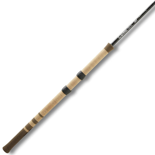 The G. Loomis STR1563 CP GLX Center Pin Fishing Rod features a sleek black shaft, cork handle, and two darker grips artfully spaced. Positioned diagonally from top right to bottom left on a white background, this elegant and functional model exemplifies G. Loomis craftsmanship.