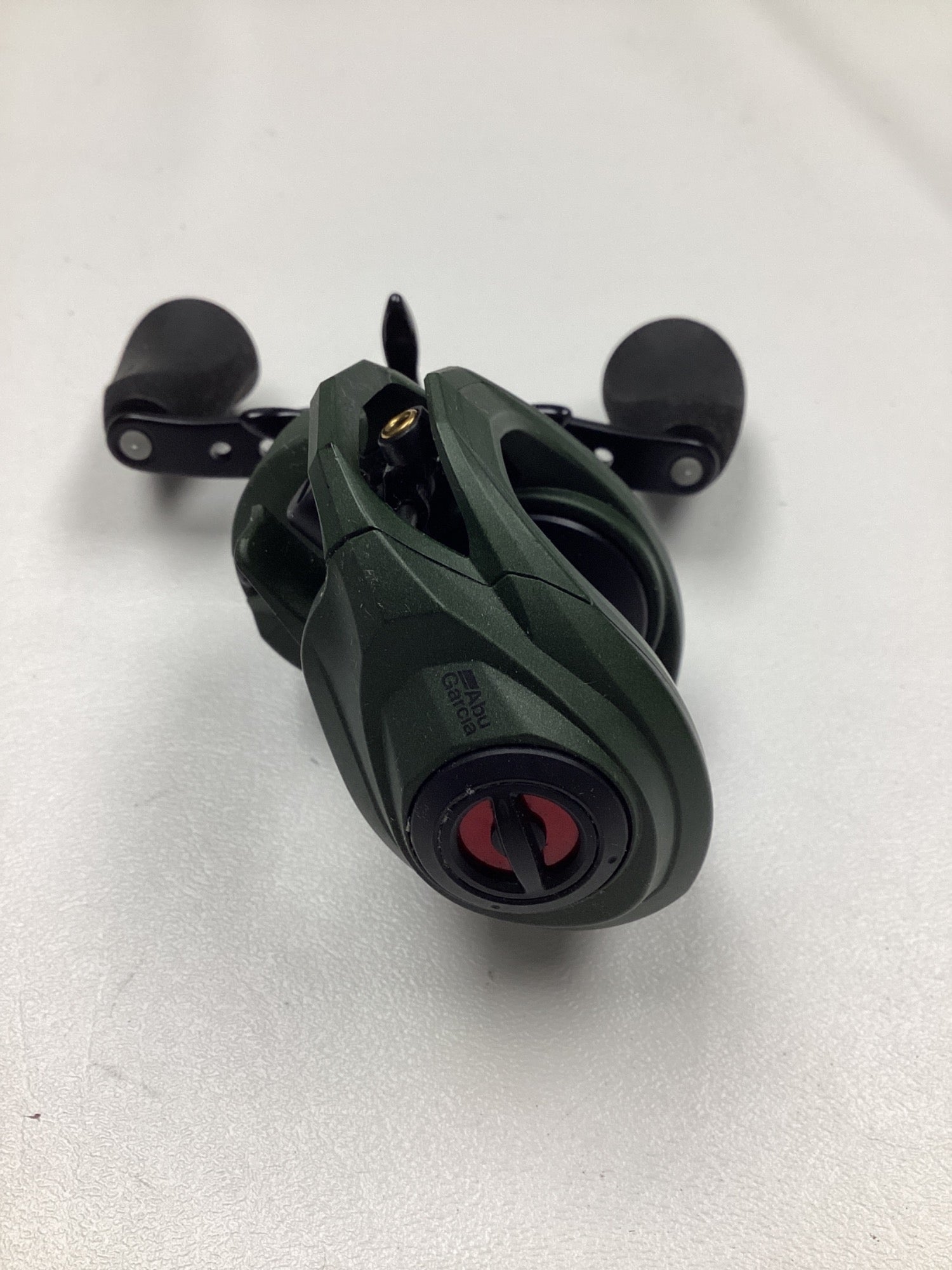 The Abu Garcia Zata 7.1:1 Right Hand casting reel by Abu Garcia, featuring a green and black design with two black handles, is shown in excellent used condition on a white surface.