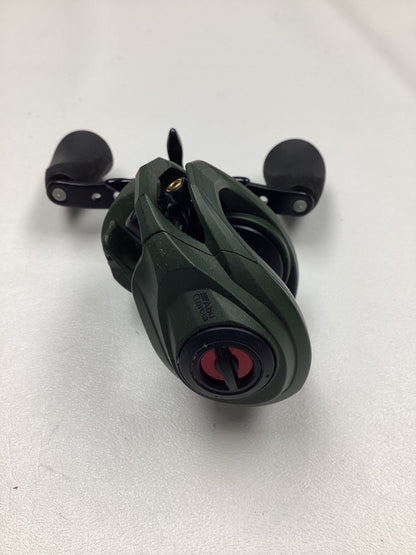 The Abu Garcia Zata 7.1:1 Right Hand casting reel by Abu Garcia, featuring a green and black design with two black handles, is shown in excellent used condition on a white surface.