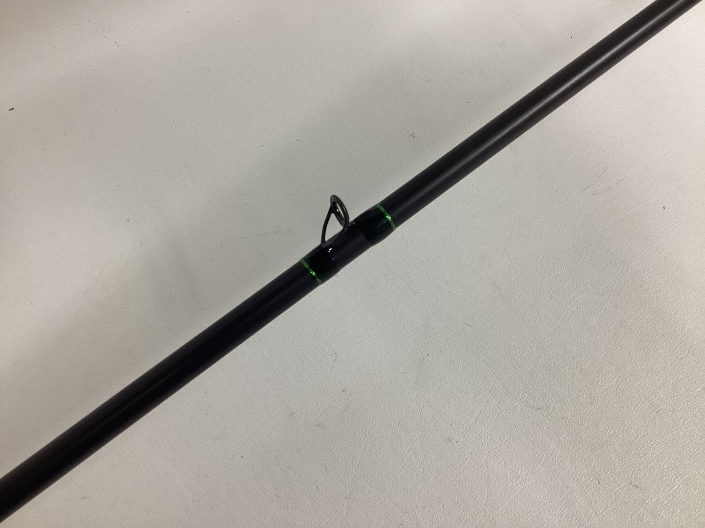 A close-up of the G. Loomis IMX-PRO Frog Rod 885C TWFR 7'4" Mag Heavy—used, in excellent condition—with black and green accents and a single line guide, ideal for anglers or those interested in our rod and reel trade-in program.