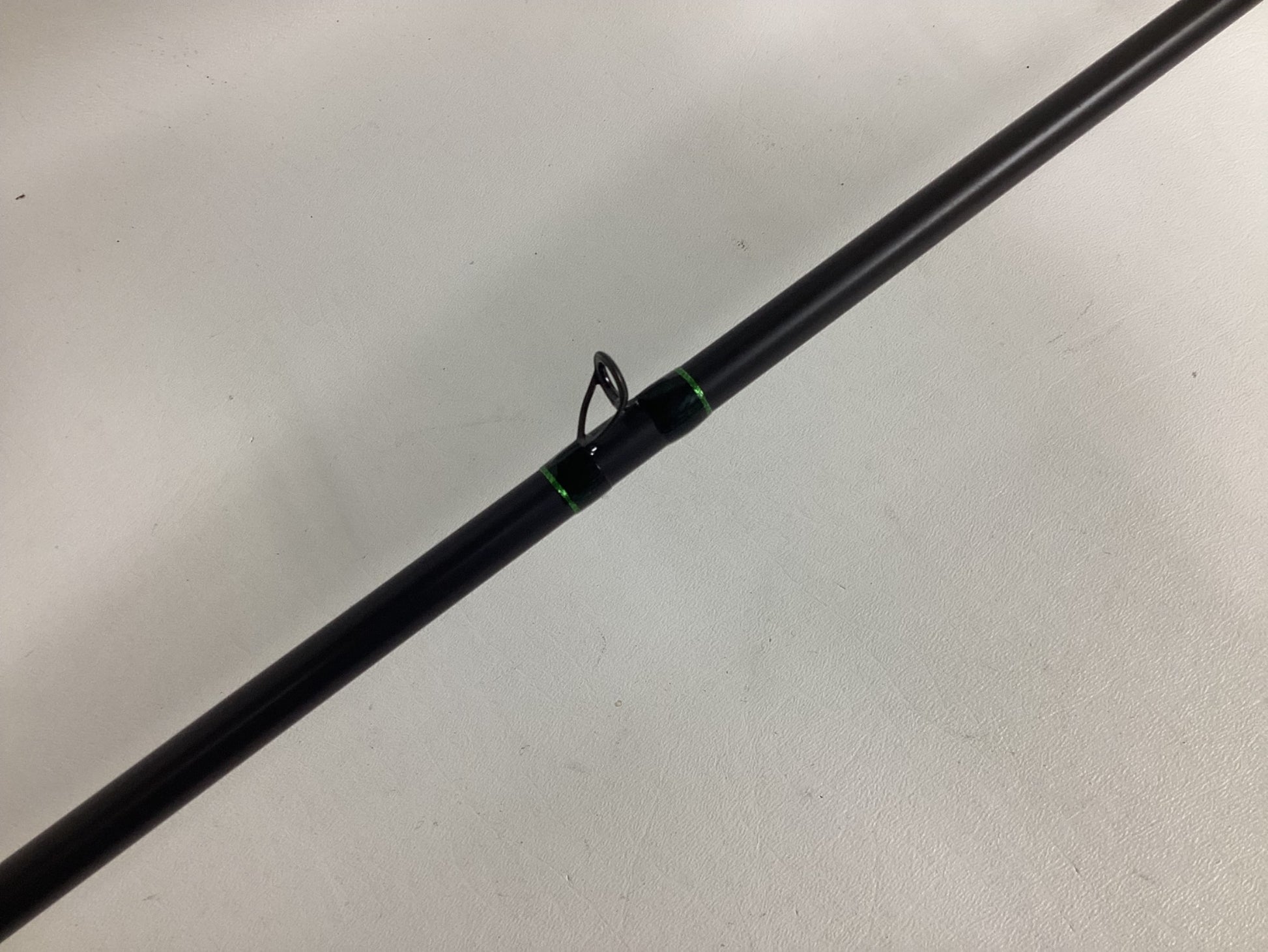 A close-up of the G. Loomis IMX-PRO Frog Rod 885C TWFR 7'4" Mag Heavy—used, in excellent condition—with black and green accents and a single line guide, ideal for anglers or those interested in our rod and reel trade-in program.