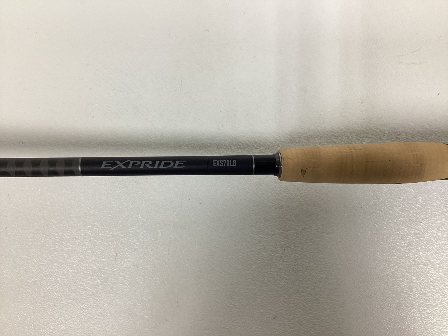 A Shimano Expride B EXS70LB spinning rod featuring a light brown grip and black shaft is displayed on a plain white background.