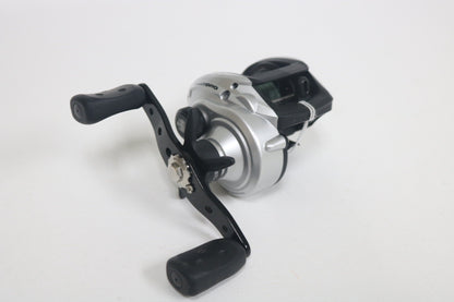 An Abu Garcia MAXTORO 5.3:1 casting reel in silver and black with dual handles, used in very good condition, displayed on a plain white background.