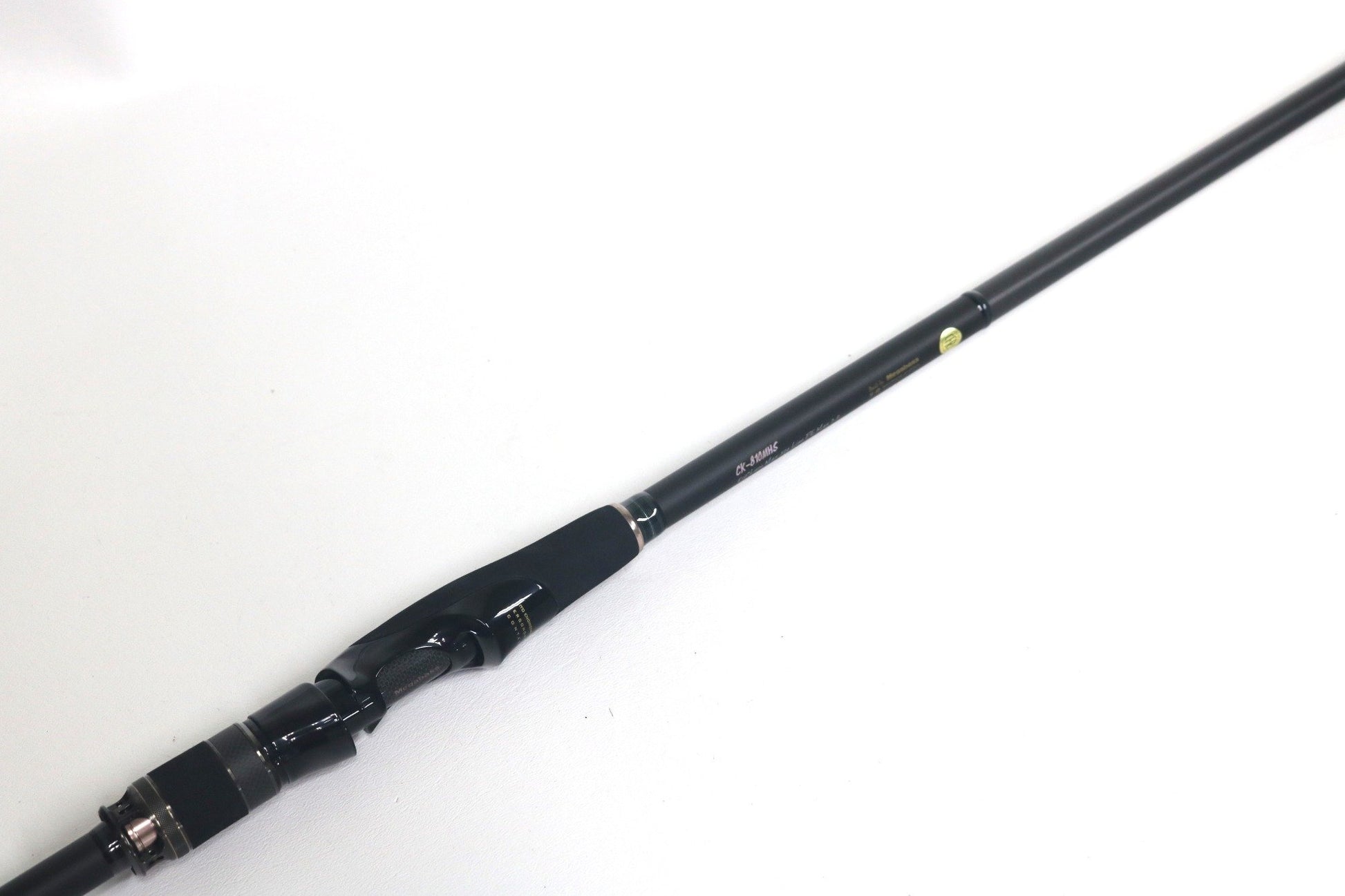 The used Megabass Cookai Inshore Spinning Rod - CK810MHS in excellent condition features a reel seat and grip, displayed diagonally on white—ideal for upgrading through our Rod and Reel Trade-In Program for store credit.