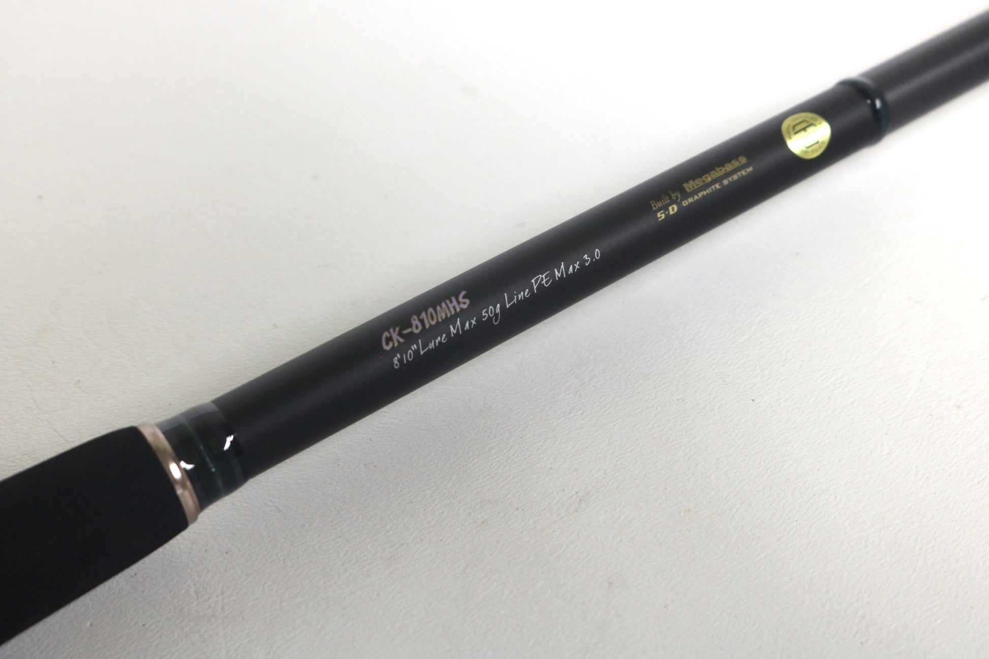 A close-up of a Megabass Cookai Inshore Spinning Rod - CK810MHS, black with gold and white text, used in excellent condition—ideal for our Rod and Reel Trade-In Program if you want store credit or quality used gear.