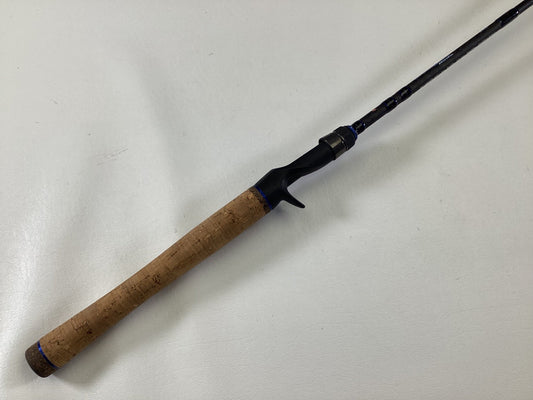 The Dobyns Champion XP DC685CB Used Casting Rod by Dobyns, in excellent condition, features a cork handle and black reel seat, displayed diagonally on a white surface.