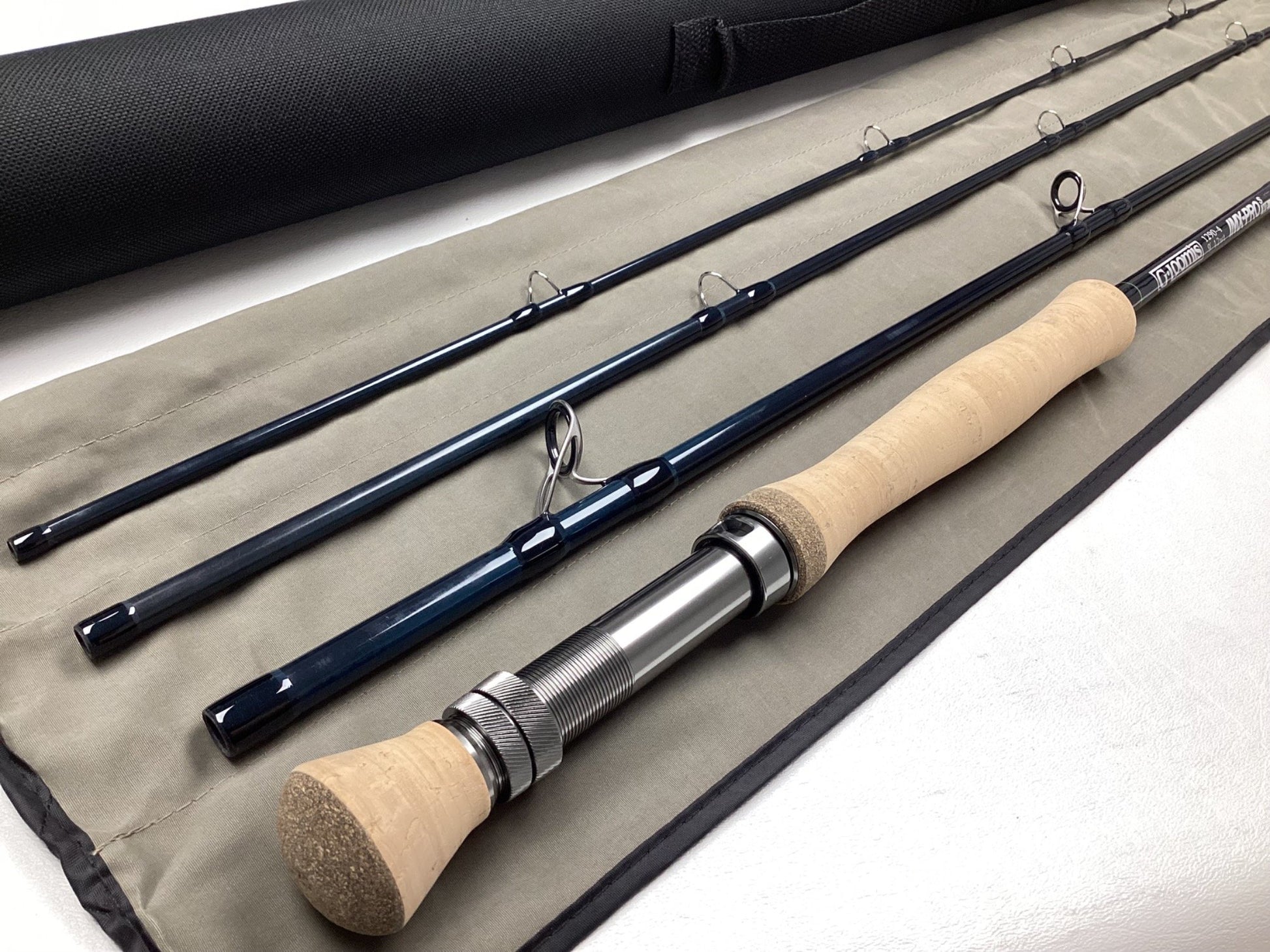The G. Loomis IMX-PRO V2S Saltwater 1290-4 9'0" #12 Used Fly Rod—Mint Condition—is displayed on its fabric case with a black carrying tube, ideal for those exploring our Rod and Reel Trade-In Program.