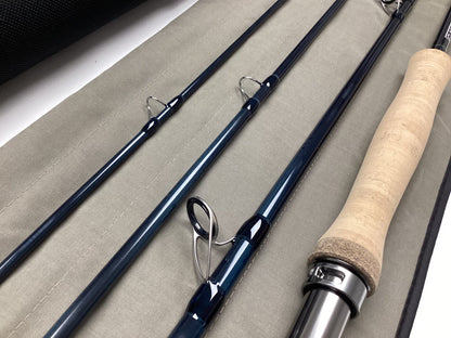 Close-up of a disassembled G. Loomis IMX-PRO V2S Saltwater 1290-4 9'0" #12 Used Fly Rod in mint condition with cork handle and blue segments on a gray case, next to a black tube—ideal for our Rod and Reel Trade-In Program.