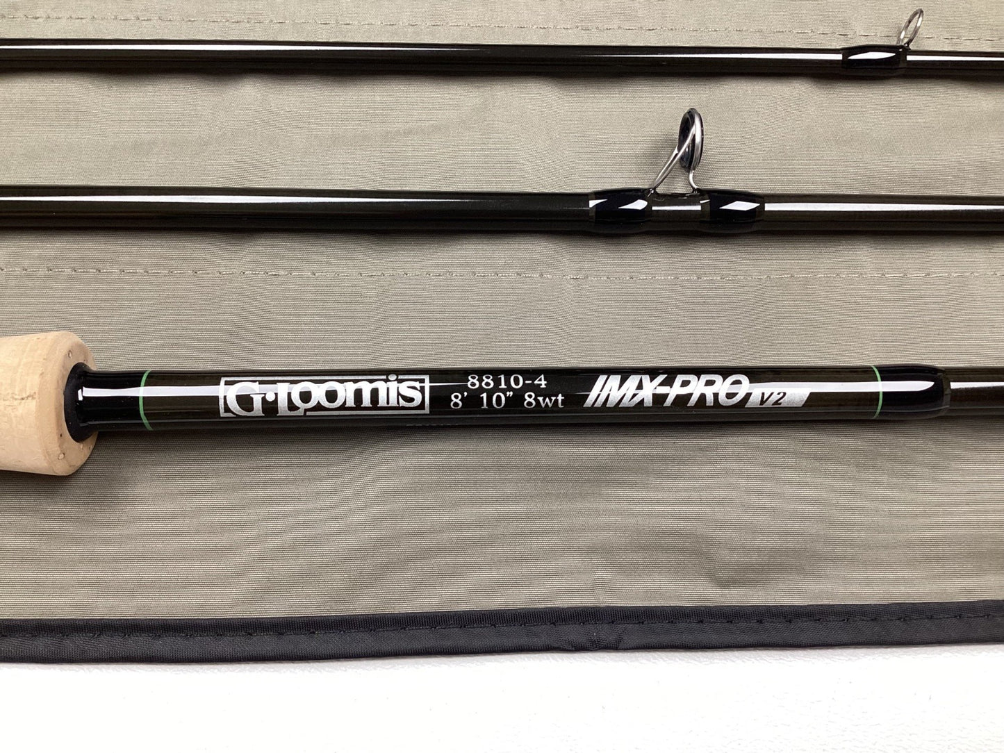 A G. Loomis IMX-PRO V2 Fly Rod 8810-4 8'10" #8 - Used Fly Rod in mint condition is shown on a light gray fabric, ideal for anglers interested in our rod and reel trade-in program.