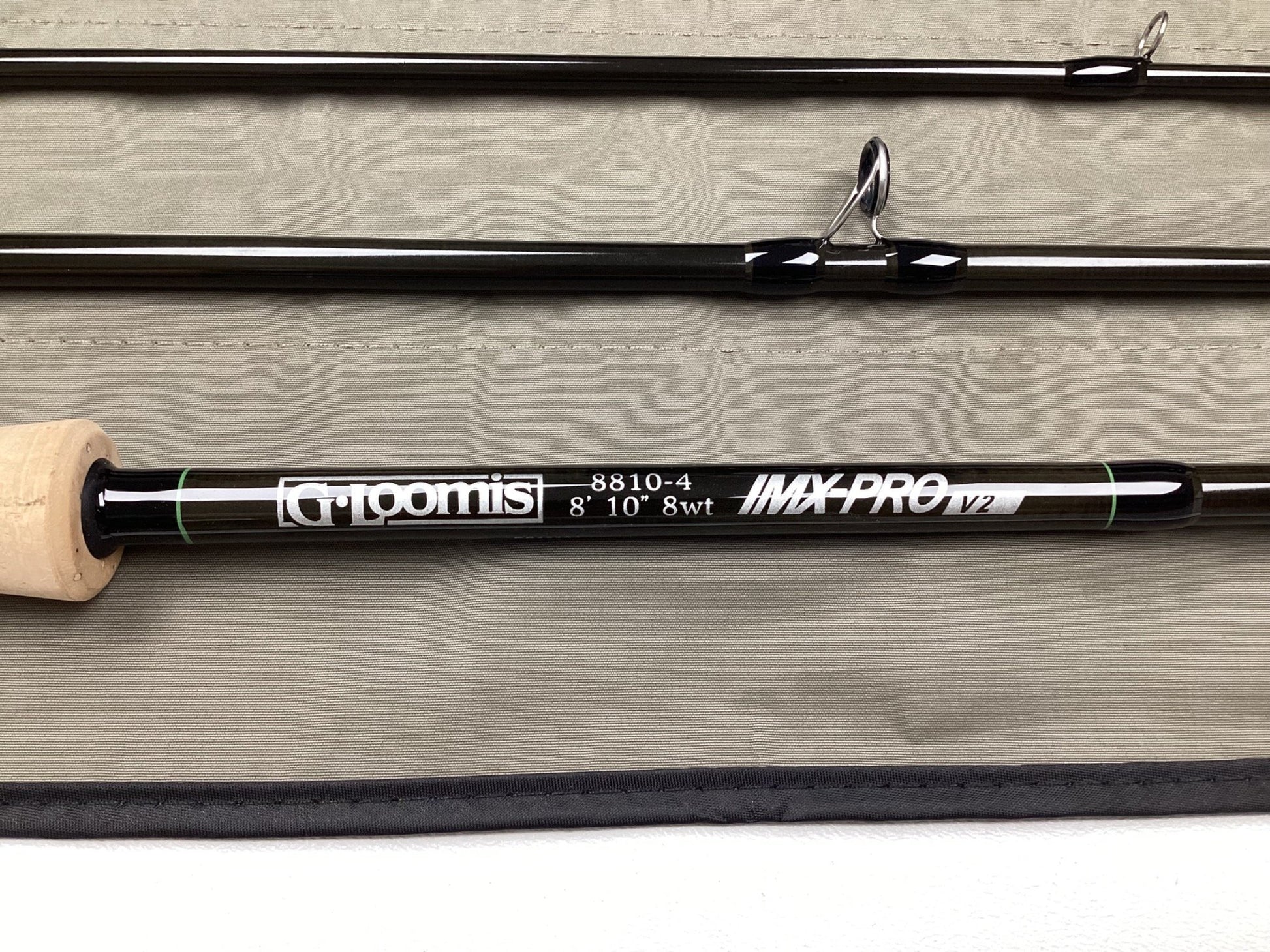 A G. Loomis IMX-PRO V2 Fly Rod 8810-4 8'10" #8 - Used Fly Rod in mint condition is shown on a light gray fabric, ideal for anglers interested in our rod and reel trade-in program.