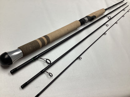 The G. Loomis IMX-PRO Steelhead Centerpin Rod 13200-4CP STR 11'0" Ultra Light (Used - Mint Condition) is a four-piece rod with black sections, line guides on each piece, and a cork grip handle, shown disassembled on a white surface.