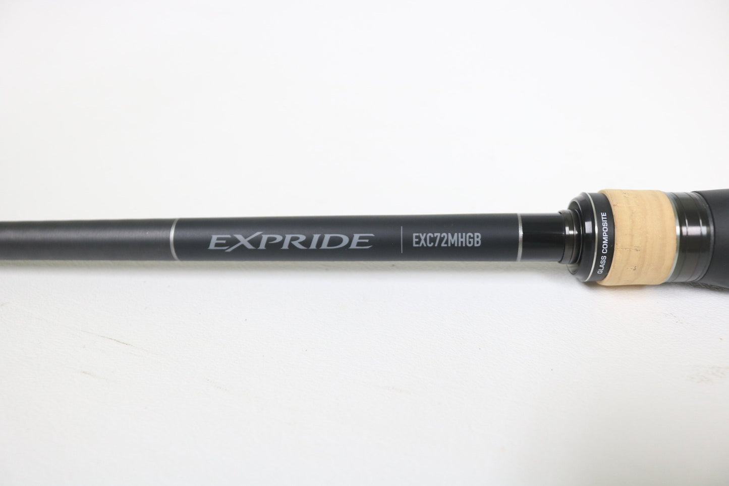 A close-up of a Shimano Expride B EXC72MHGB 7'2" Medium Heavy Glass Casting Rod in excellent used condition, featuring a black and tan handle—ideal for anglers considering our rod and reel trade-in program.