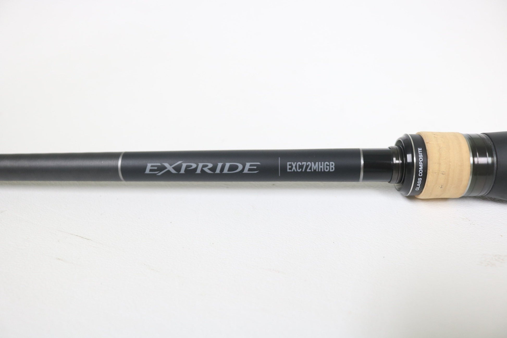 A close-up of a Shimano Expride B EXC72MHGB 7'2" Medium Heavy Glass Casting Rod in excellent used condition, featuring a black and tan handle—ideal for anglers considering our rod and reel trade-in program.