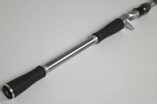 A close-up of a Daiwa Tatula Elite TAEL801MHRBG 8'0" Medium Heavy used casting rod in good condition with a black handle, silver body, and trigger grip, displayed on a plain white surface.