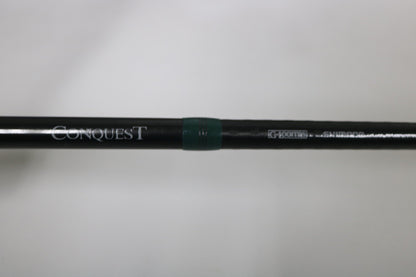 A close-up of a G. Loomis Conquest CNQ 904C MBR 7'6" Heavy Used Casting Rod in very good condition, with "Conquest" and "G. Loomis" printed on it and a green ring near the center. Ideal for our Rod and Reel Trade-In Program. Plain out-of-focus background.